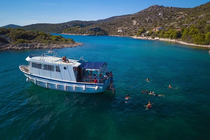 Personen, die in einer Bucht um ein weißes Ausflugsboot schwimmen und entspannen.