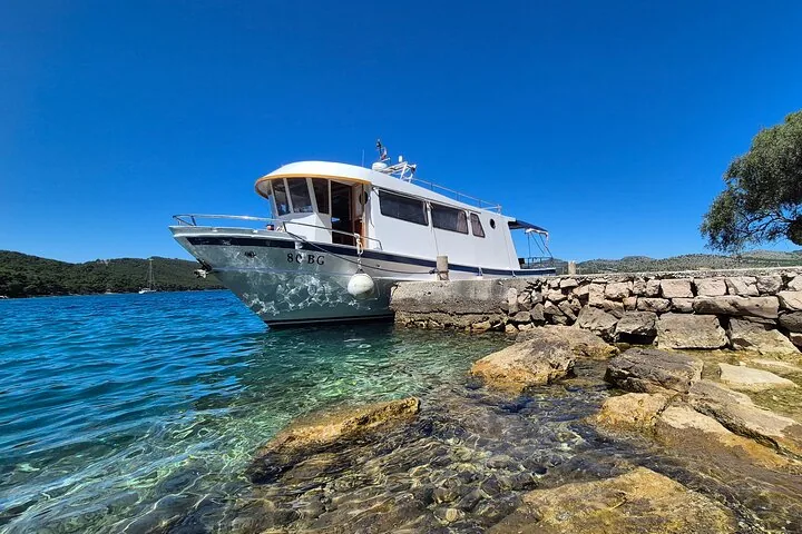Ein Ausflugsboot, das an einem Steinpier bei klarem Wasser festgemacht ist.