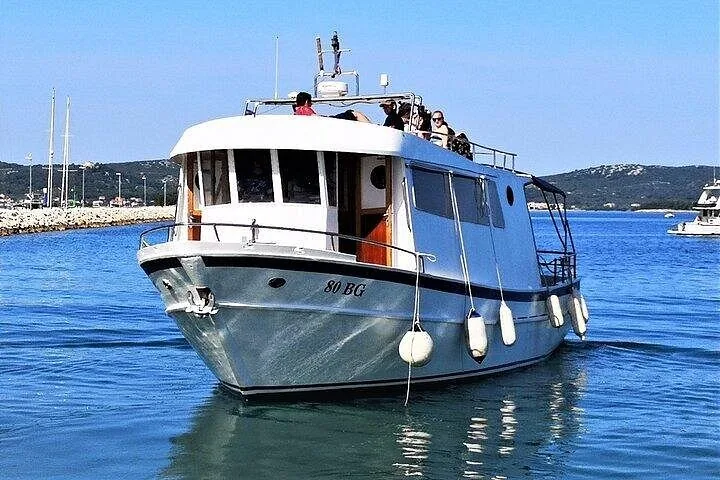 Ein weißes Ausflugsboot fährt auf dem ruhigen blauen Wasser der Kornati.