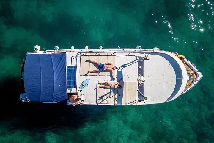 Luftaufnahme von Menschen, die auf dem Deck eines Ausflugsboots sonnenbaden.